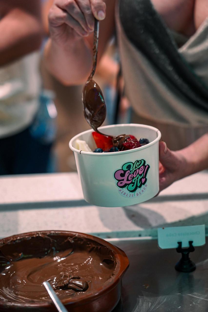 Chocolate drizzle being added to a Yo Love It frozen yoghurt cup
